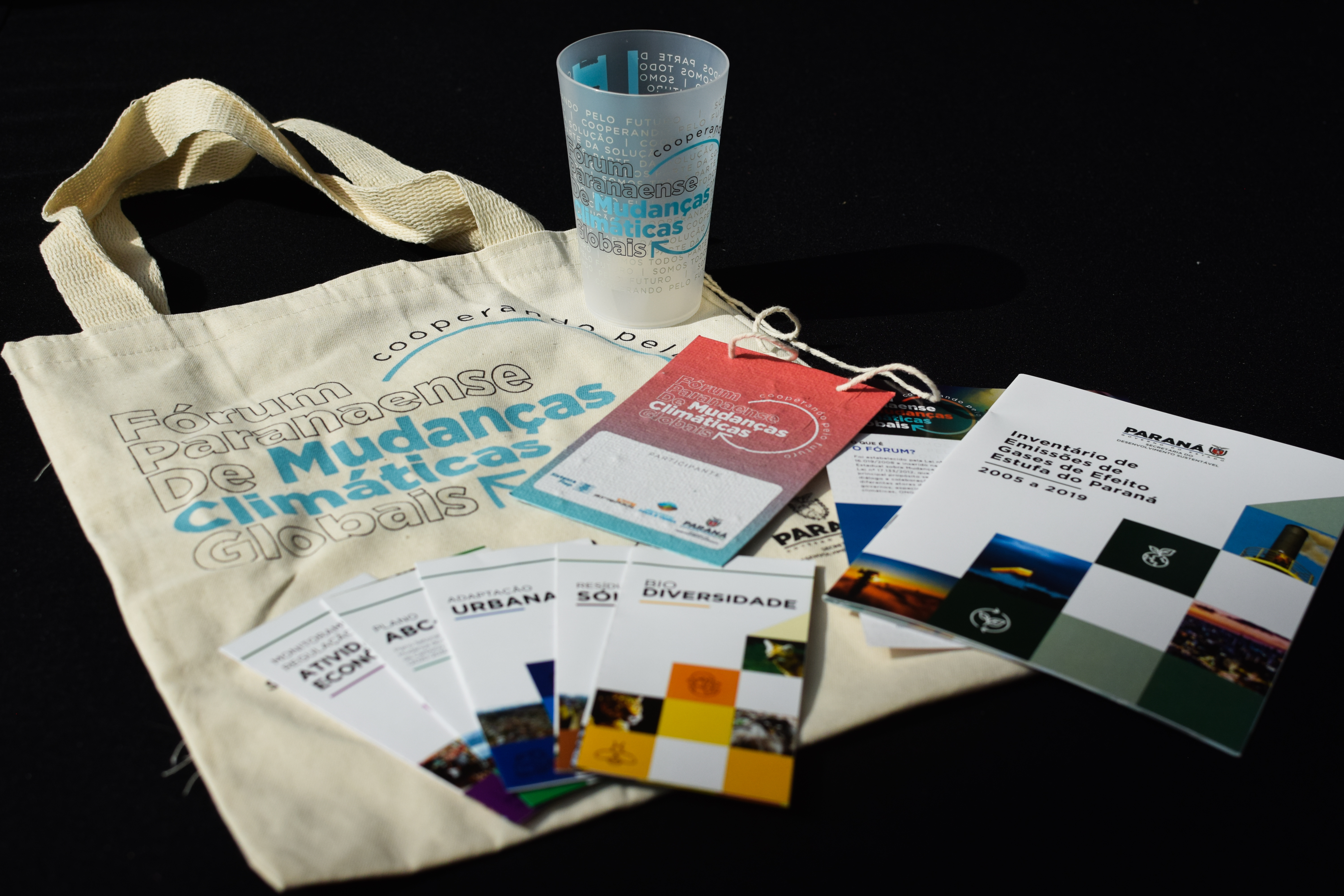 Materiais gráficos e ecobag distribuídos durante o evento do Fórum.